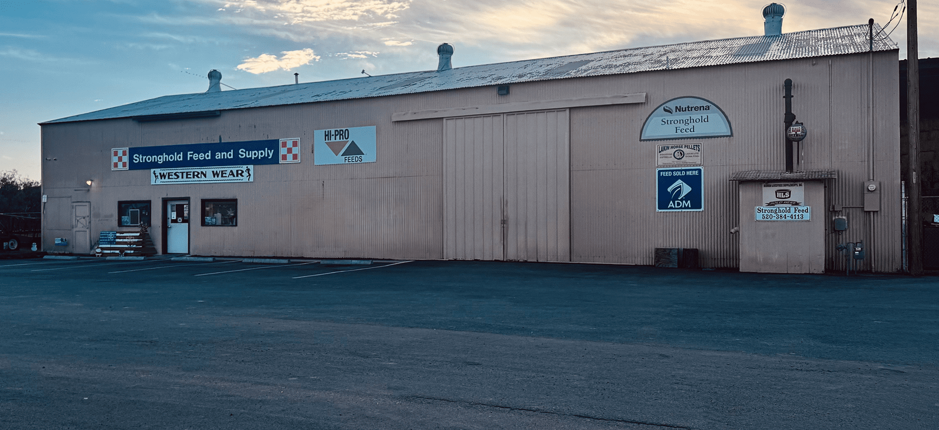 Warehouse exterior with signs and parking lot.