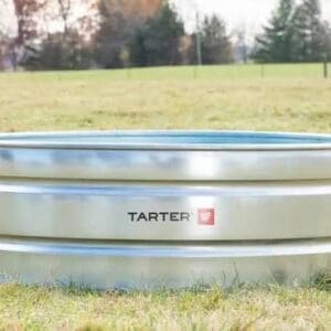 A Yarter metal livestock water trough outdoors on grassy field.