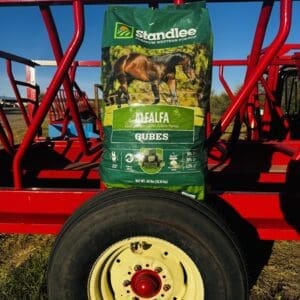 Two bags of dog food placed on a tractor tire in a farm setting.
