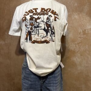 White graphic tee with cowboys and text "Just Rode In" paired with blue jeans.