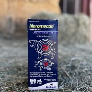 Bottle of Noromectin dewormer for cattle with dosage syringe on hay.