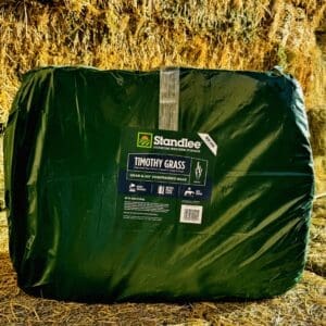 A packed green sleeping bag on a textured surface.