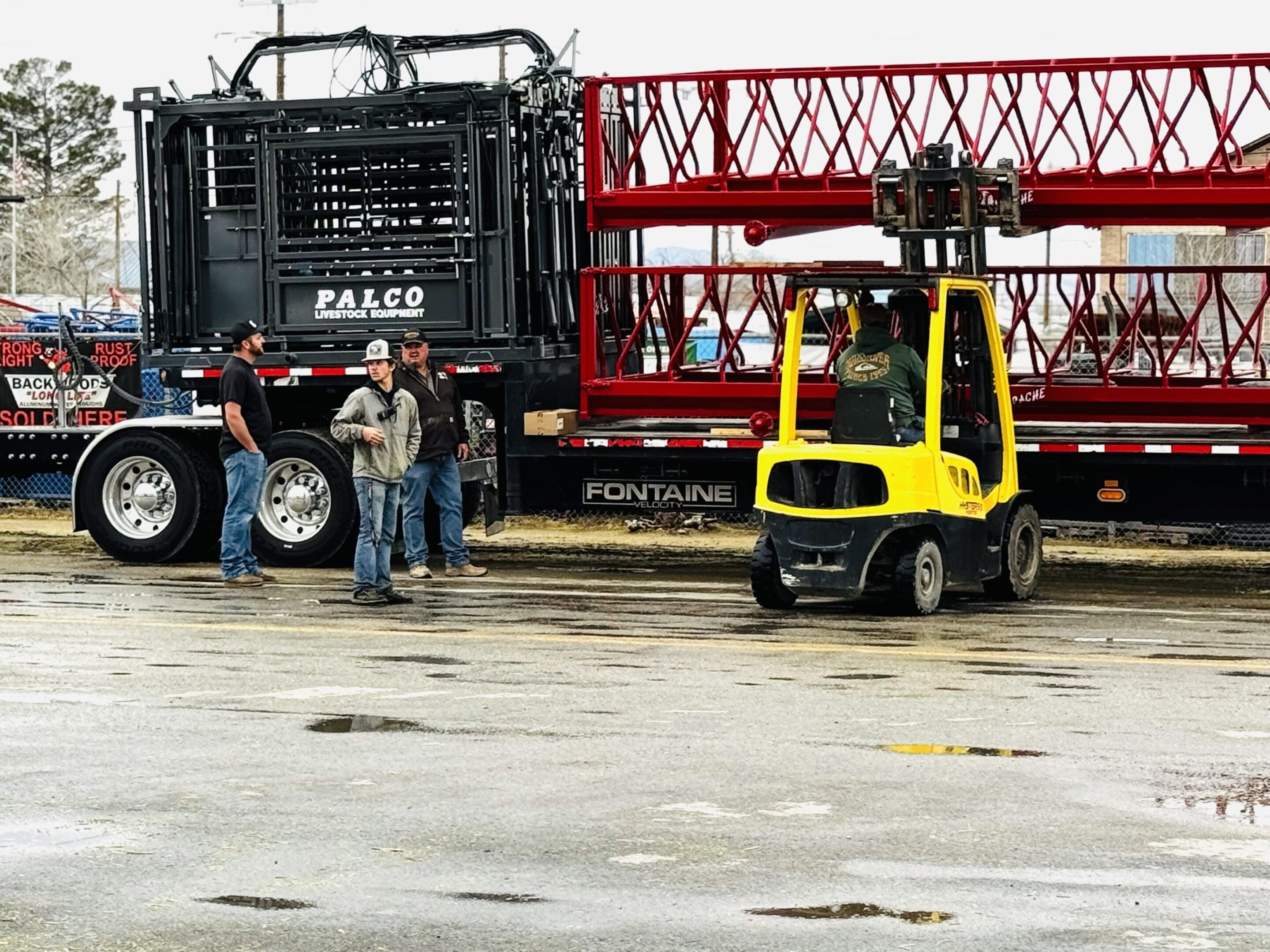 Workers operate heavy machinery on a wet concrete site.