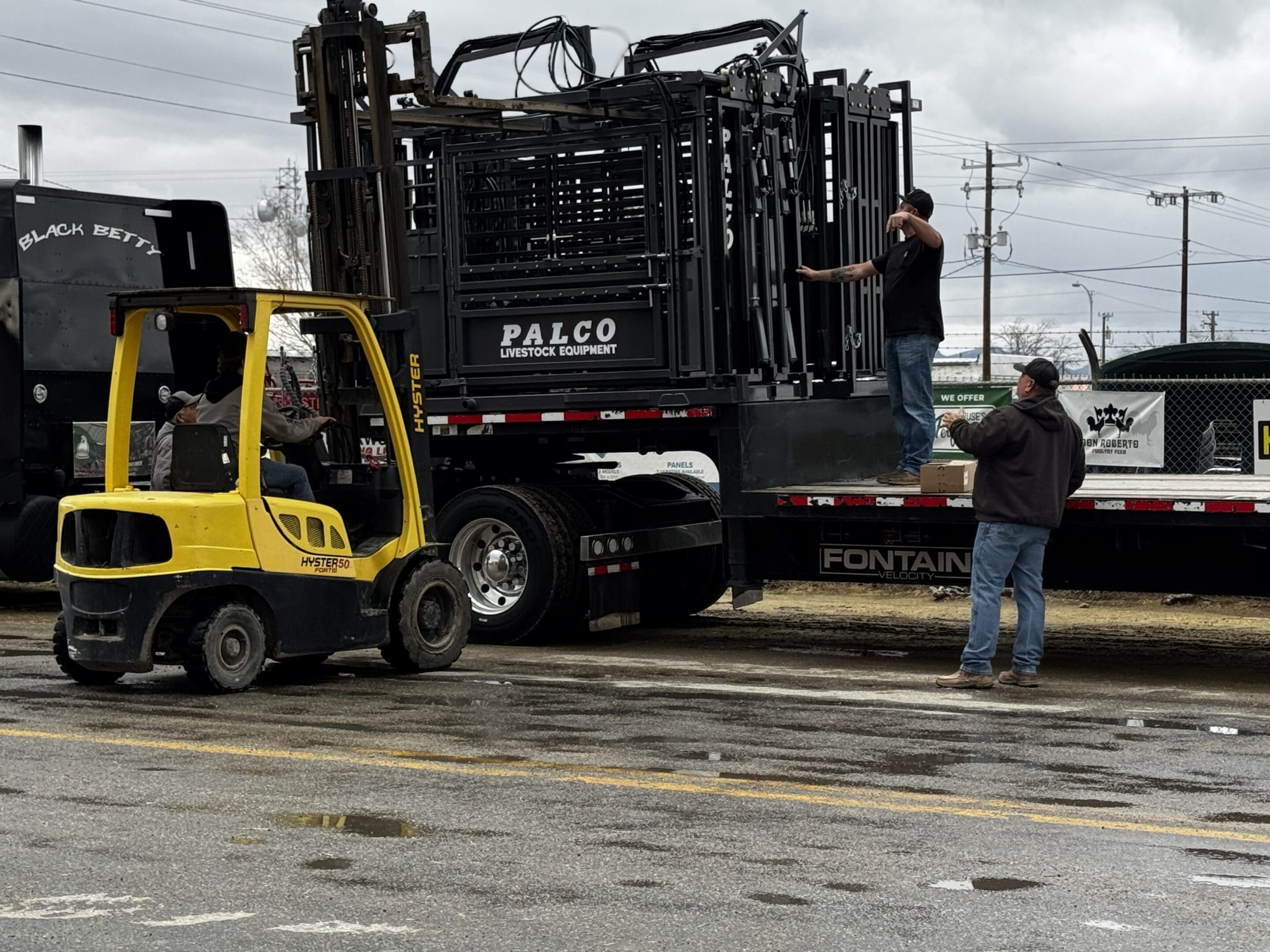 Workers unloading equipment from a large truck using a forklift.